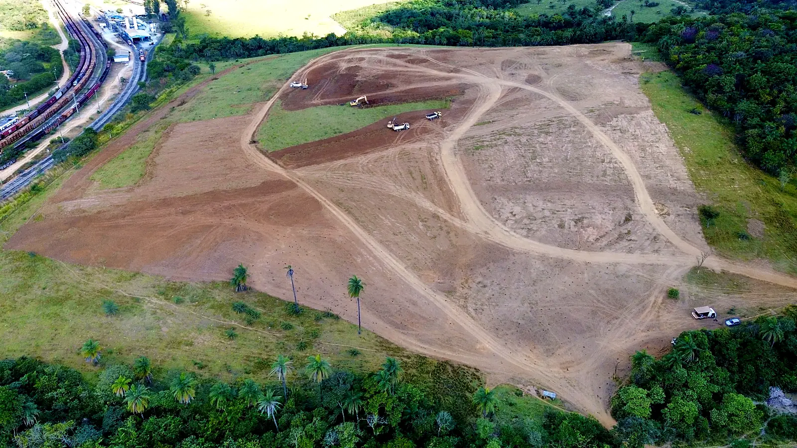 Antes: início da terraplenagem, com escavadeira e caminhões basculantes abrindo o terreno
